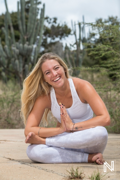 A Young Woman Practices Yoga Outdoors in a Serene Garden Setting, Demonstrating a Seated Pose With a Joyful Expression on a Sunny Day