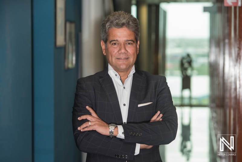 A Confident Businessman Posing With Crossed Arms in a Modern Office Corridor During Daylight With Reflections in the Background