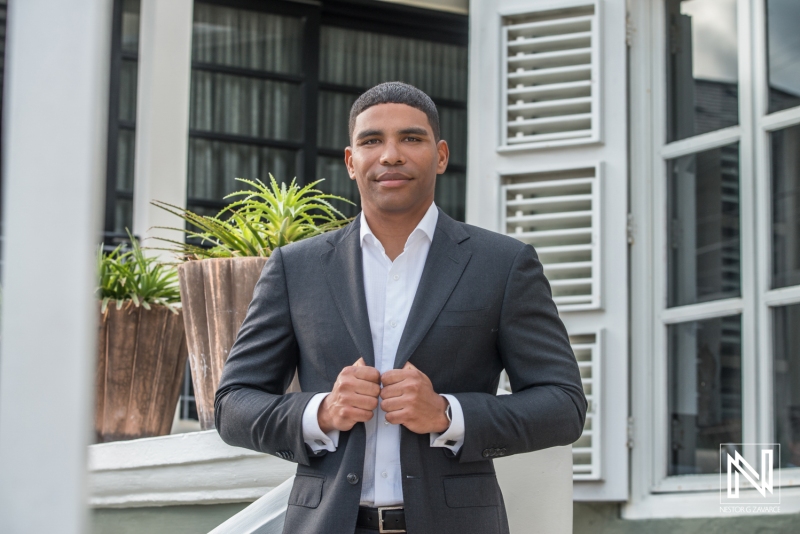 A Well-Dressed Man Stands Confidently Outside a Modern Building, Adjusting His Blazer in a Professional Setting During Daylight Hours