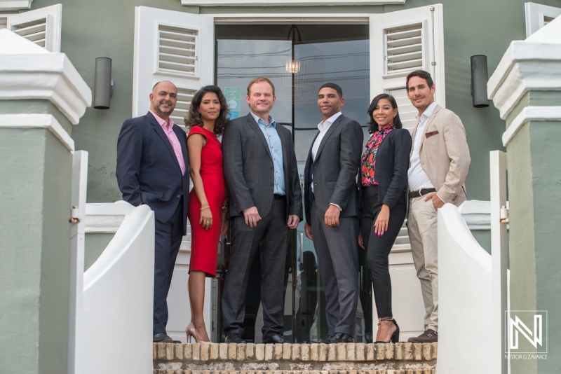 A Professional Group of Six Individuals Poses for a Photo Outside a Modern Building With White Shutters, Showcasing Teamwork and Collaboration in a Business Setting