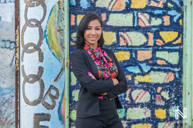 A Confident Professional Woman Poses With Crossed Arms in Front of Vibrant Street Art in an Urban Setting During Daylight Hours