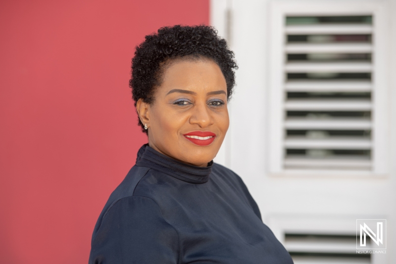 Portrait of a Confident Woman Standing Against a Vibrant Red Wall in a Stylish Black Top, Exuding Charisma and Elegance During Daylight