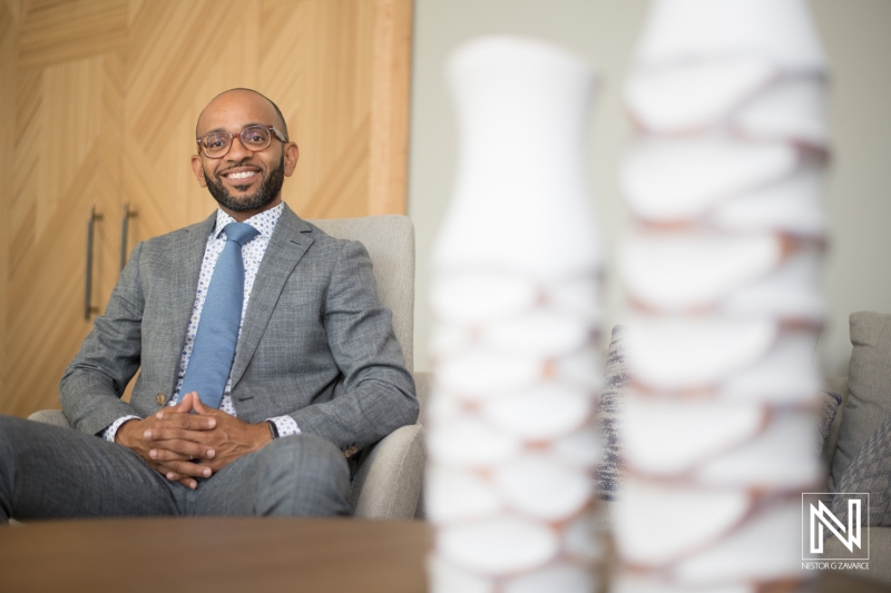 A Professional Man in a Suit Sits Comfortably in an Elegantly Designed Office, Posing Confidently Next to Modern Decorative Vases