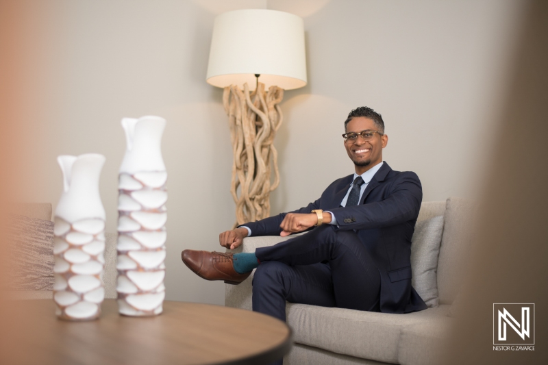 A Well-Dressed Man Sits Confidently on a Modern Couch in a Stylishly Decorated Living Room With Unique Decor During Daytime