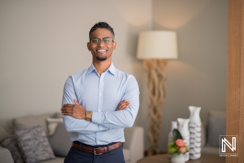 A Confident Young Professional Stands With Crossed Arms in a Modern Living Room, Showcasing a Stylish Atmosphere During Daylight