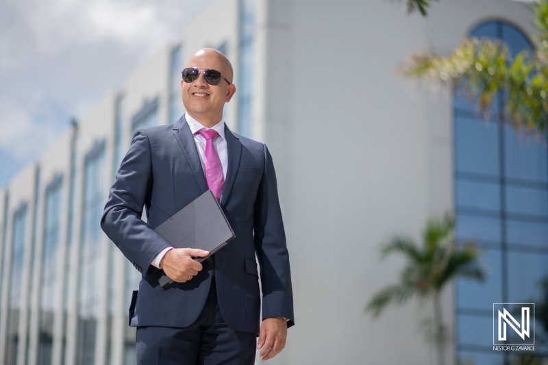 Business Professional in Formal Attire Wearing Sunglasses Stands Confidently Outside a Modern Office Building During a Sunny Day