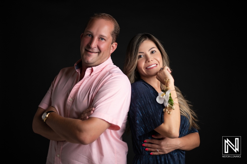 A Smiling Couple Poses Confidently With Their Arms Crossed in a Studio Setting Against a Dark Backdrop During a Professional Photoshoot