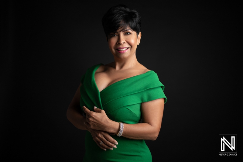 A Confident Woman in a Green Dress Poses Gracefully Against a Dark Backdrop, Showcasing Her Elegance and Vibrant Expression During an Indoor Photo Session