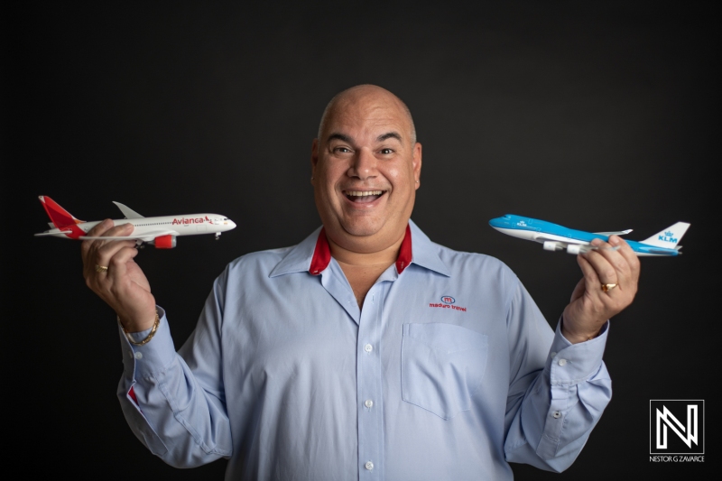 A Man Proudly Holds Model Airplanes Representing Two Different Airlines, Showcasing His Passion for Aviation at a Studio in Daylight