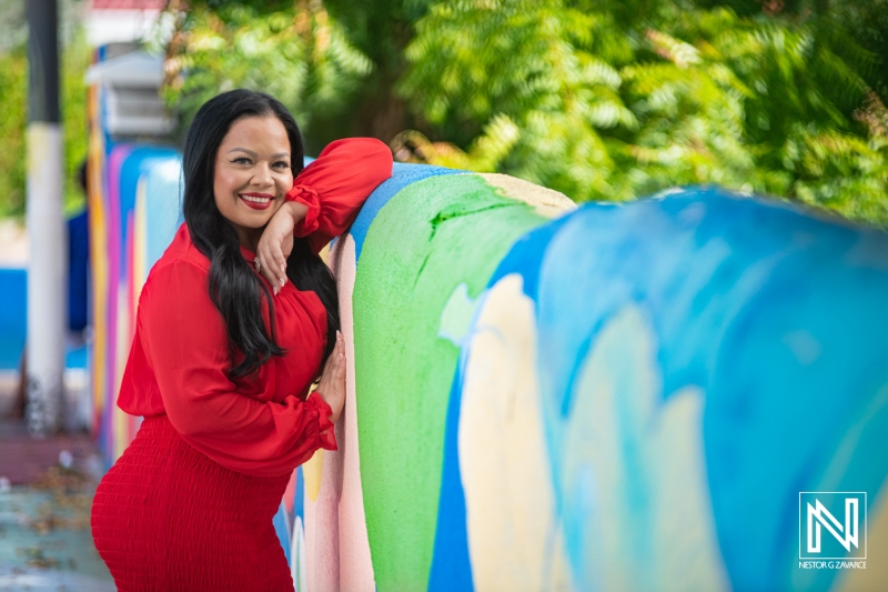 A Woman in a Red Dress Poses Against a Vibrant Mural in a Tropical Setting, Showcasing Beauty and Confidence on a Sunny Day