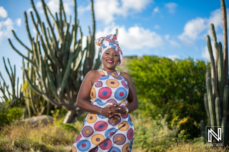 A Woman in Traditional Attire Stands Confidently Among Tall Cactus Plants Under a Bright Blue Sky in a Vibrant Outdoor Setting, Capturing the Essence of Cultural Pride and Natural Beauty