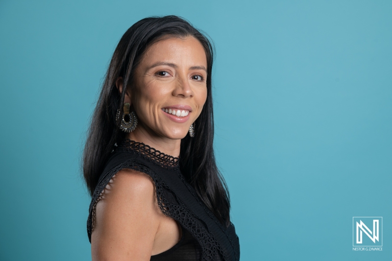 A Woman With Long Black Hair and Elegant Earrings Poses With a Slight Smile Against a Bright Blue Background During a Professional Photoshoot