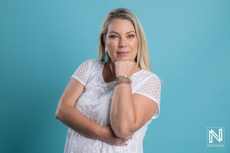 A Confident Woman Poses Against a Bright Blue Backdrop Showcasing Her Relaxed Demeanor in Casual Attire During a Sunny Afternoon