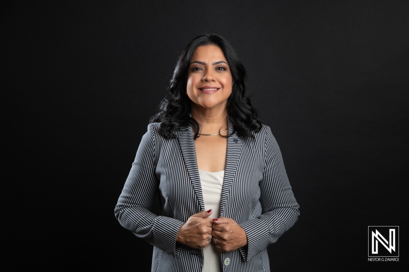 Professional Woman in a Striped Blazer Stands Confidently Against a Solid Black Background, Showcasing Her Stylish Attire and Engaging Smile