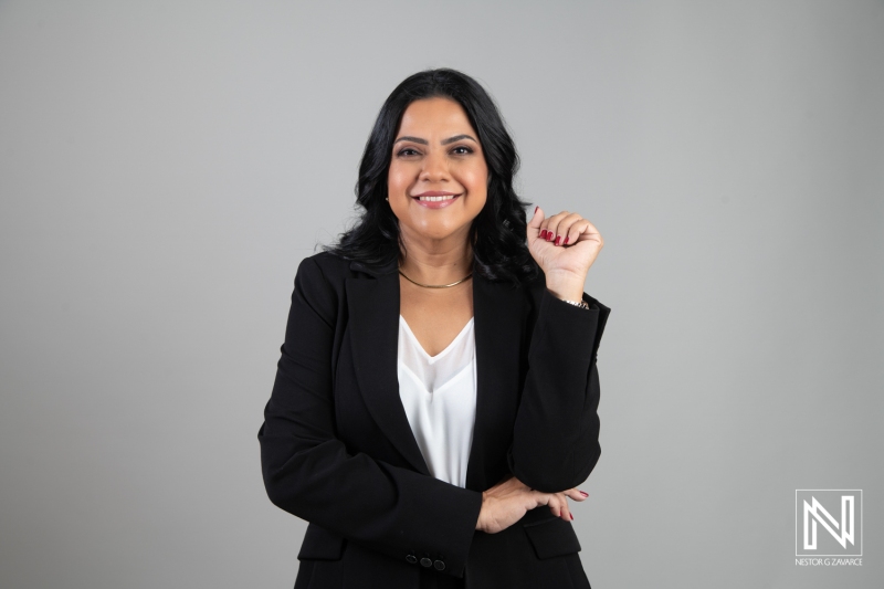 Confident Businesswoman Smiling in a Professional Outfit Against a Light Gray Backdrop During a Photoshoot