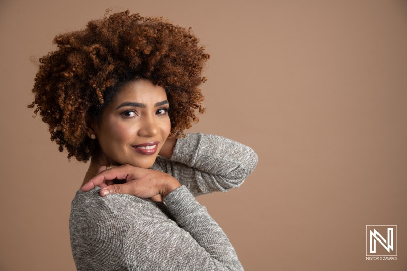 A Woman With Curly Hair Poses Confidently Against a Neutral Backdrop, Showcasing Her Unique Hairstyle and Vibrant Personality During a Studio Photo Session