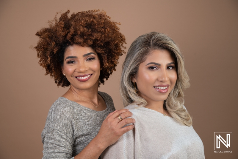 Two Women With Stylish Hairstyles Pose Together in a Studio Setting, Showcasing Natural Curls and Straight Hair Against a Warm, Neutral Background