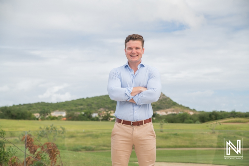 A Man Stands Confidently With Arms Crossed on a Scenic Outdoor Location Featuring Rolling Hills and a Cloudy Sky, Showcasing a Relaxed Atmosphere in the Mid-Afternoon Light