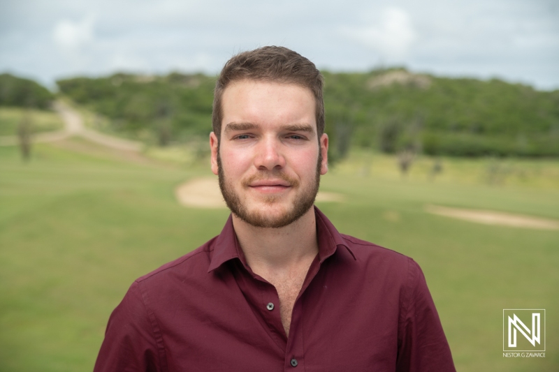 Young Man Standing Outdoors in a Scenic Area, Showcasing a Relaxed Expression Under Bright Skies, With Lush Green Landscape in the Background, Suggesting a Casual Afternoon