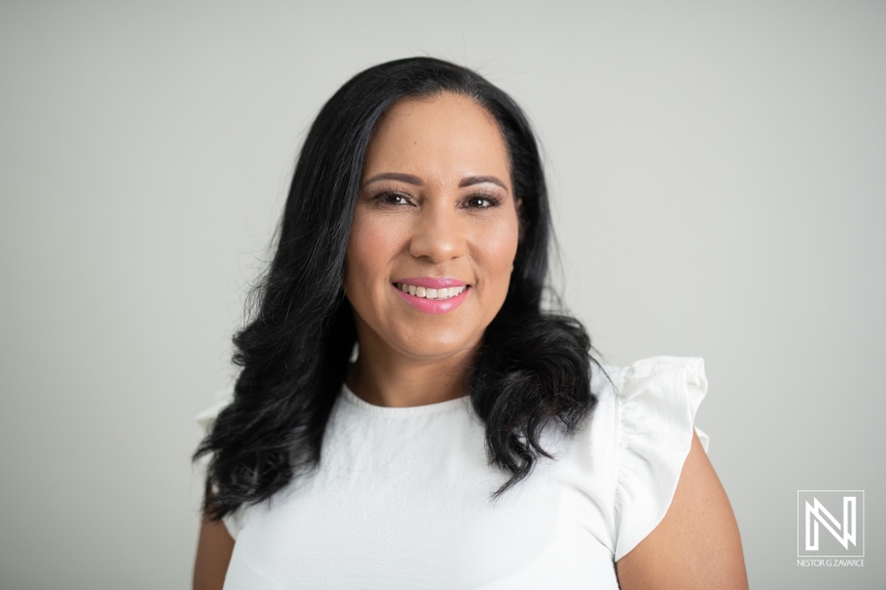 A Woman in a White Blouse Smiles Warmly Against a Neutral Backdrop During a Professional Portrait Session in a Modern Studio Setting