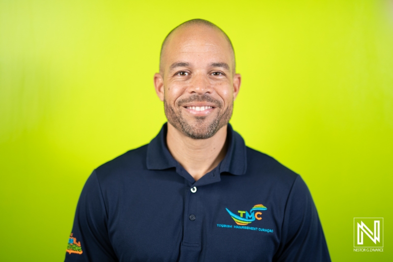 A Man With a Friendly Smile Stands in Front of a Vibrant Green Backdrop, Wearing a Navy Polo Shirt, Showcasing Confidence and Approachability in a Professional Setting