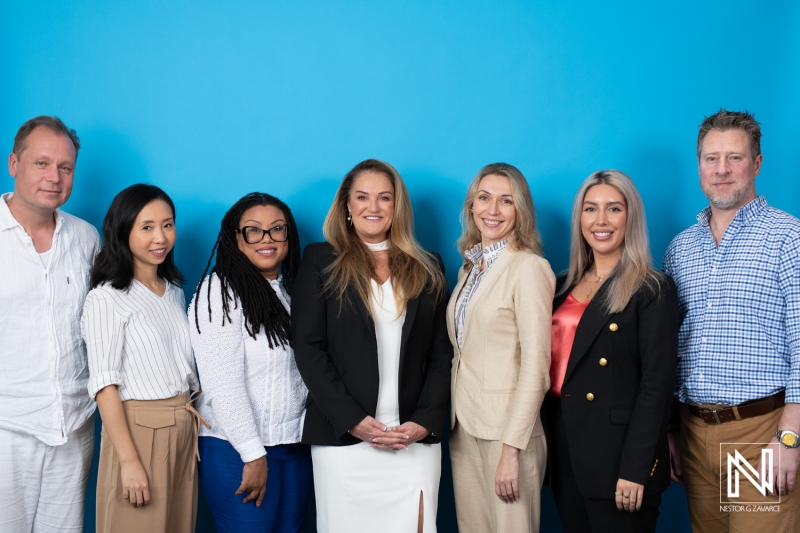 A Diverse Group of Professionals Poses Together Against a Bright Blue Backdrop During a Business Networking Event in an Urban Setting