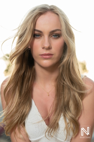 Young Woman With Long Blonde Hair Poses Outdoors in Natural Light, Showcasing Her Confident Expression and Casual Style Against a Blurred Background