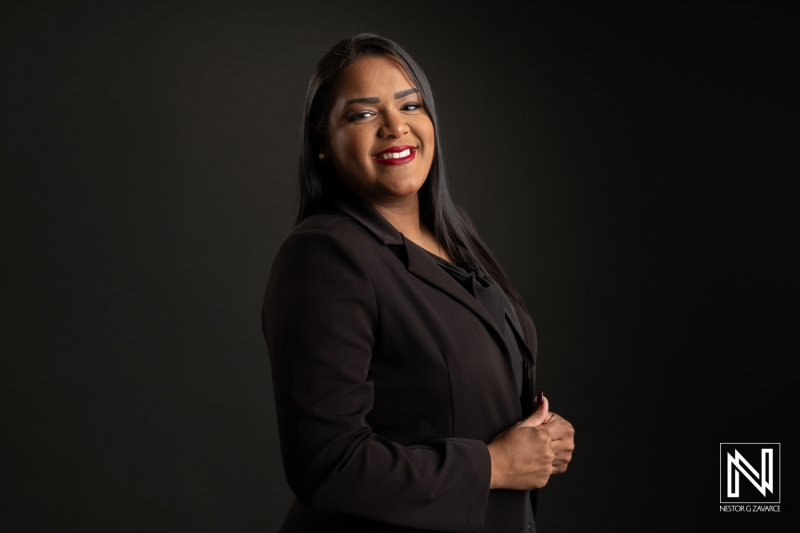 Confident Professional in a Business Suit Poses Against a Dark Backdrop While Showcasing a Warm Smile and Engaging Presence During a Portrait Session