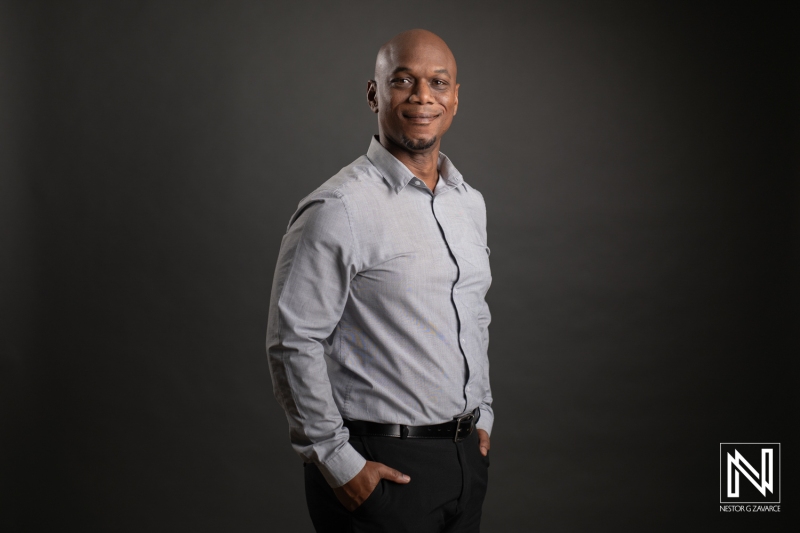 Professional Portrait of a Confident Man in a Light Gray Shirt Against a Dark Background, Showcasing a Friendly Demeanor and Business-Ready Pose