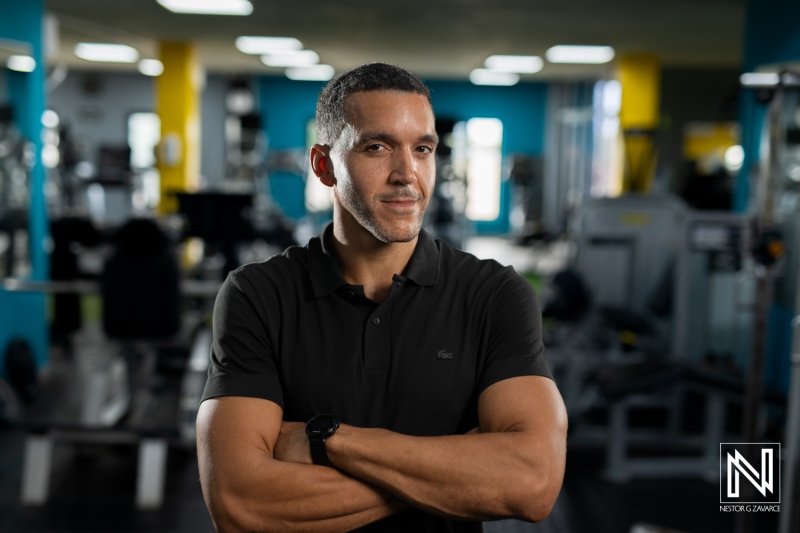 A Confident Man Stands With Crossed Arms in a Colorful Gym, Showcasing Strength and Determination During a Lively Workout Session