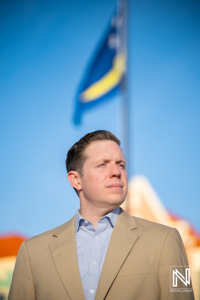 Corporate headshot taken in Curacao with a clear blue sky and local flag in the background