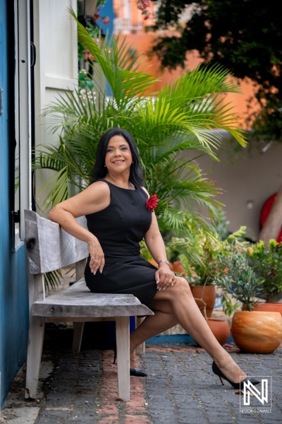 Corporate headshot in Curacao featuring a professional sitting outdoors with plants and colorful background
