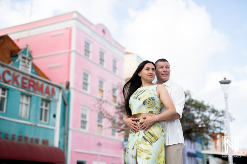 A Couple Enjoys a Romantic Moment in Front of Colorful Buildings During a Sunny Day in a Vibrant Caribbean Town