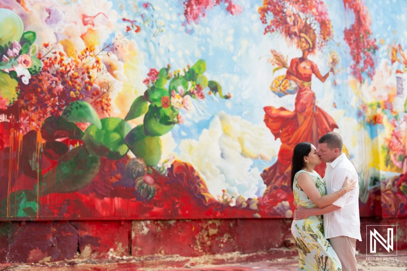 Couple Sharing a Romantic Moment in Front of a Vibrant Mural With Floral and Mythical Designs in a Lively Urban Setting During Daytime