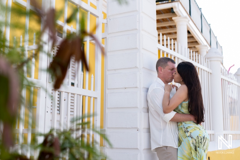 Romantic Couple Sharing a Kiss Against a Vibrant Yellow Wall in a Serene Outdoor Setting During a Sunny Afternoon