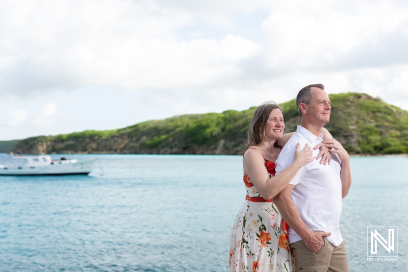 A Couple Enjoys a Romantic Moment by the Serene Waters of the Caribbean, With Lush Green Hills and a Boat in the Background on a Sunny Day