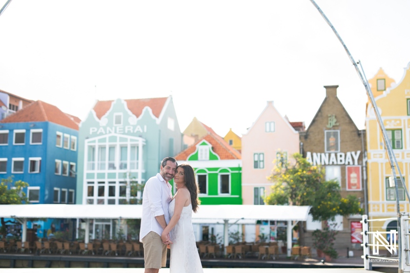 Couple enjoying a romantic moment at Handelskade, Curacao, surrounded by vibrant buildings and clear blue skies