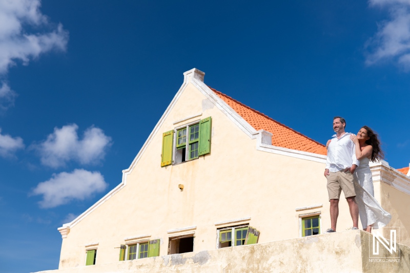 Couple enjoying a sunny day at Cas Abao Beach in Curacao with picturesque architecture and blue skies