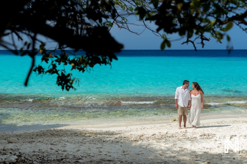 Couple enjoys a romantic walk along the soft sands of Cas Abao Beach in Curacao on a clear sunny day