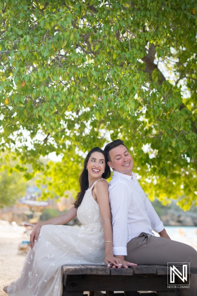 Couple enjoys a joyful moment at Cas Abao Beach in Curacao under the lush greenery during a sunny day