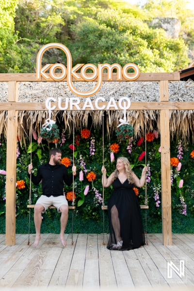 Couple enjoying swings at Kokomo in Curacao surrounded by vibrant flowers during a sunny day