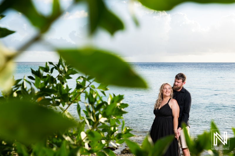 Romantic couple enjoying a serene moment by the beach in Curacao during sunset while surrounded by lush greenery