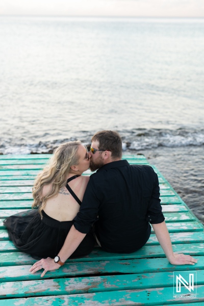 Romantic couple sharing a kiss on a wooden dock in Curacao during sunset near the calm ocean waters