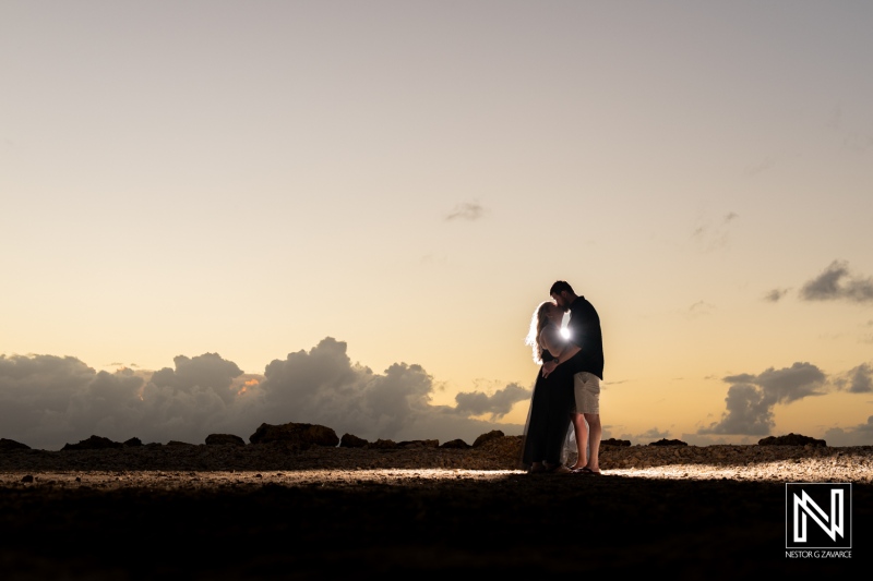 Couple sharing a romantic moment under the sunset in Curacao with silhouetted clouds
