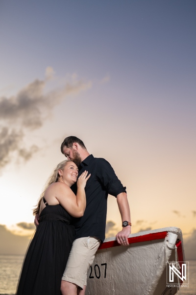 Couple embracing on a boat in Curacao at sunset, capturing an intimate moment on the beautiful Caribbean coast