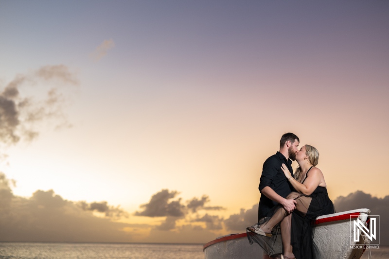 Romantic couple sharing a kiss on a boat in Curacao at sunset