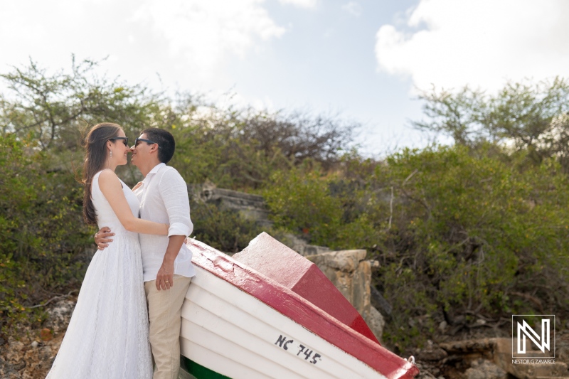 Couple enjoys romantic sunrise embrace at Playa Porto Mari in Curacao with a colorful boat as a backdrop