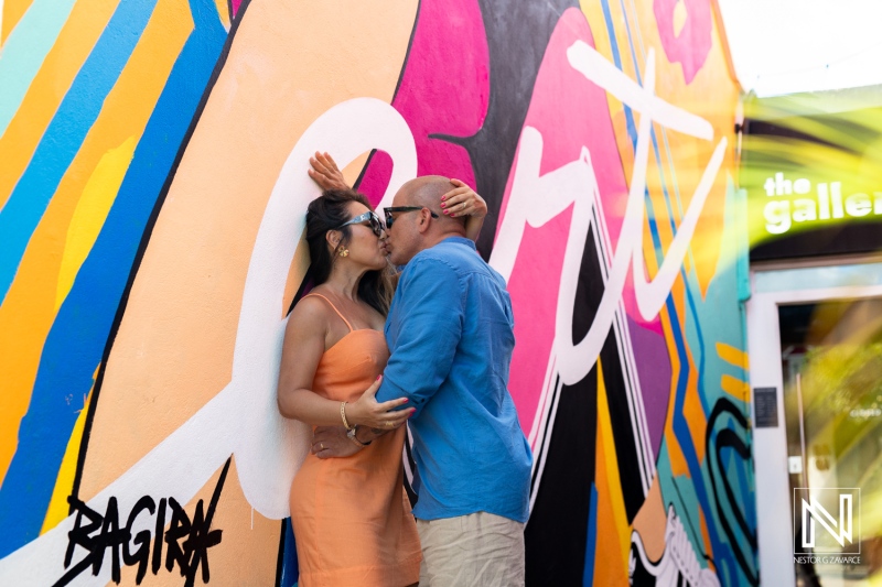 Couple shares an affectionate moment against a vibrant mural in Curacao during their romantic photoshoot