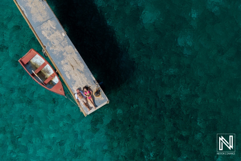 Couple enjoys a romantic moment on a dock in Curacao surrounded by clear turquoise waters during a sunny day