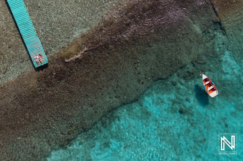 Couple enjoys a romantic photo session on a dock by the clear waters of Curacao during a sunny day